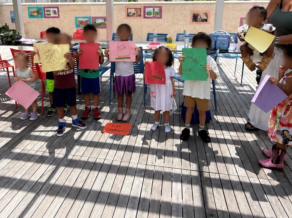 Children sharing colorful community drawings at a CurioSpark gathering