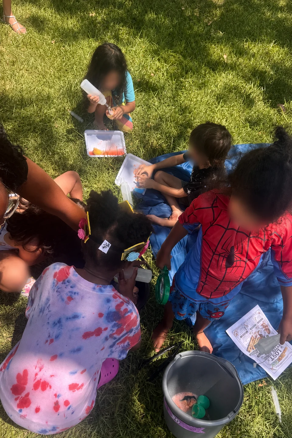 Children gathered on the grass for a hands-on CurioSpark science activity